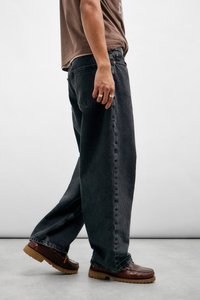 Bredde ben sorte denimjeans med en falmet finish, med side lommer og subtile søm detaljer. Kombinert med brune lærersko.