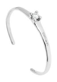 Pulsera de mancuernas de plata con un brillante cristal transparente en el centro, acabado pulido suave y detalles grabados en un lado. Diseño curvado simple.