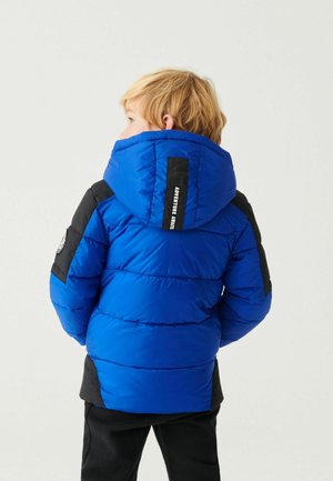 Giacca a vento blu con dettagli neri, dotata di cappuccio, design trapuntato e un'etichetta sul retro. La giacca presenta una texture liscia e lucida.
