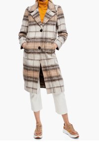 Abrigo de cuadros en tonos beige, marrón y naranja, con cuello, botones de doble fila, detalles de bolsillo y un diseño de longitud media.