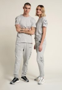 Szary zestaw odzieży sportowej składający się z t-shirtów krótko rękawowych i zwężających się spodni, zdobiony kontrastowymi grafikami w zygzaki oraz różnorodnymi fakturami.