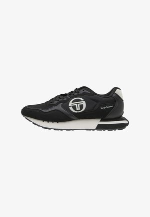 Zapatilla Sergio Tacchini en blanco y negro con cordones al frente, logo en el lateral y suela acolchada diseñada para uso casual.