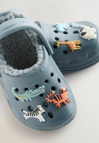 Kék műanyag gyermekklumpák szürke, bolyhos béléssel, állat alakú kitűzőkkel: krokodil, tigris, zebra és zsiráf.