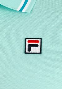 Polo shirt azzurro chiaro con un tessuto testurizzato, caratterizzato da un piccolo logo ricamato in un quadrato con accenti rossi e neri.