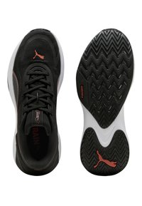 Chaussures de sport noires avec une tige texturée, des accents ton sur ton et une semelle intermédiaire blanche. Elles présentent une semelle noire à motif en zigzag et un logo bien visible.