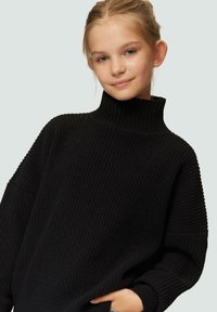 Zwarte gebreide turtleneck trui van een textuurstof, oversized pasvorm en geribbelde manchet, met een hoge halslijn en verlaagde schouders.