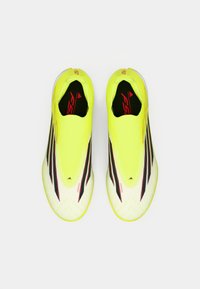 Φωτεινά κίτρινα ποδοσφαιρικά παπούτσια με υφή στο πάνω μέρος, που διαθέτουν μαύρες λεπτομέρειες και κομψή γραμμή. Ελαφρύ σχέδιο με κόσμημα τύπου κάλτσας.