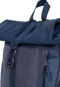 Marinblå ryggsäck med rulltoppsdesign som har en strukturerad nederdel i mesh, justerbara remmar och spänne för stängning. Tillverkad av slitstarka material.