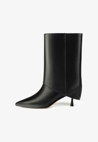 Botín de cuero negro con punta puntiaguda y tacón cónico. El diseño presenta una textura lisa y brillante con detalles de costuras minimalistas.