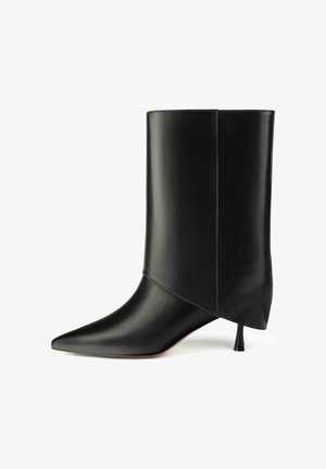 Zwarte leren enkellaars met een spitse neus, uniek gevouwen ontwerp en een kleine conische hak. Gladde textuur met minimale details.