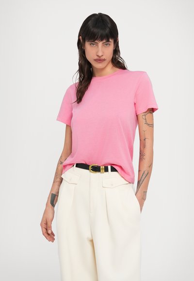Ροζ t-shirt με στρογγυλή λαιμόκοψη και κοντά μανίκια, από απαλό βαμβακερό ύφασμα. Συνδυάζεται με εκρού παντελόνια ψηλόμεσα και μαύρη ζώνη με χρυσή αγκράφα.