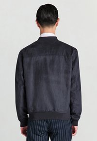 Bomber grigio scuro in tessuto liscio, con collo e polsini a coste, dal design semplice e pulito, senza elementi metallici visibili.