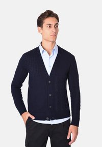 Cardigan in maglia navy con design testurizzato, scollatura a V e chiusura a cinque bottoni. Presenta una tasca frontale e polsini e orlo a costine.