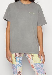 Grå oversized t-shirt i bomull med rund hals och korta ärmar. Textlogotypen "COLOURFUL REBEL" i gult på bröstet.