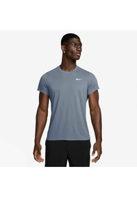 Grå kortærmet Nike træningsskjorte med rund hals, letvægtsstof og et lille hvidt logo på venstre bryst. Sorte shorts.