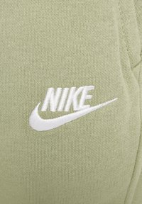 Nike világoszöld textil, amely texturált kötött mintával rendelkezik. A hímzett fehér logó a "NIKE" nevet és egy swoosh részletet tartalmaz.
