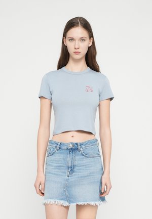 Svetlomodré krátke bavlnené tričko s malou červenou grafikou čerešne, v kombinácii s džínsovou minisukňou s ošúchaným lemom a prednými vreckami.