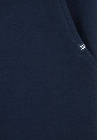 Marineblauwe katoenstof met een gladde textuur en een subtiel gebreid patroon. Bevat een klein label met een witte letter "R."