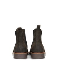Botas Chelsea de ante marrón oscuro con paneles laterales elásticos y lengüetas, con una suela de goma marrón y un diseño de punta redondeada.