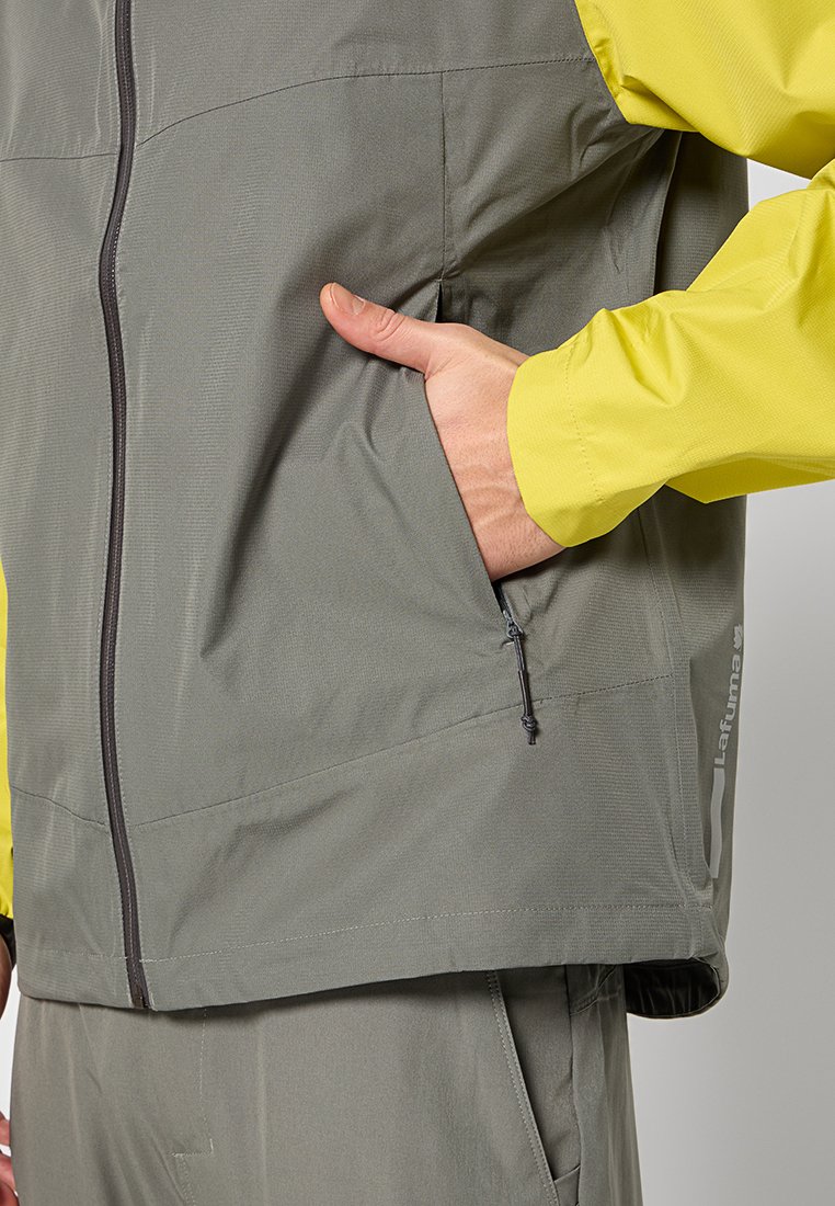 Veste extérieure légère et grise avec une fermeture éclair à l'avant, en tissu texturé et dotée d'une capuche jaune vif. Comprend des poches latérales et des accents de logo.