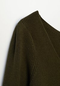 Tissu en maille côtelée vert foncé avec un détail de col roulé sur un vêtement à manches longues, présenté sur un fond uni.