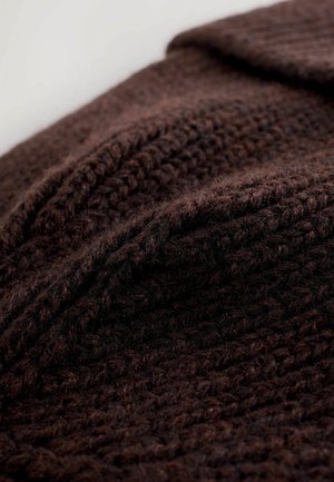 Braun gestrickter Stoff mit einer strukturierten, dicken Webart. Das Material wirkt weich und dick und weist subtile Farbvariationen auf.