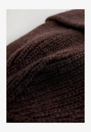 Tessuto in maglia marrone con una trama testurizzata e spessa. Il materiale sembra morbido e spesso, con leggere variazioni di colore.
