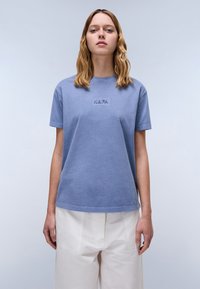 Lichtblauwe katoenen t-shirt met korte mouwen, ronde hals en geborduurd "NAPA" logo op de borst. Ontspannen pasvorm met een gladde textuur.