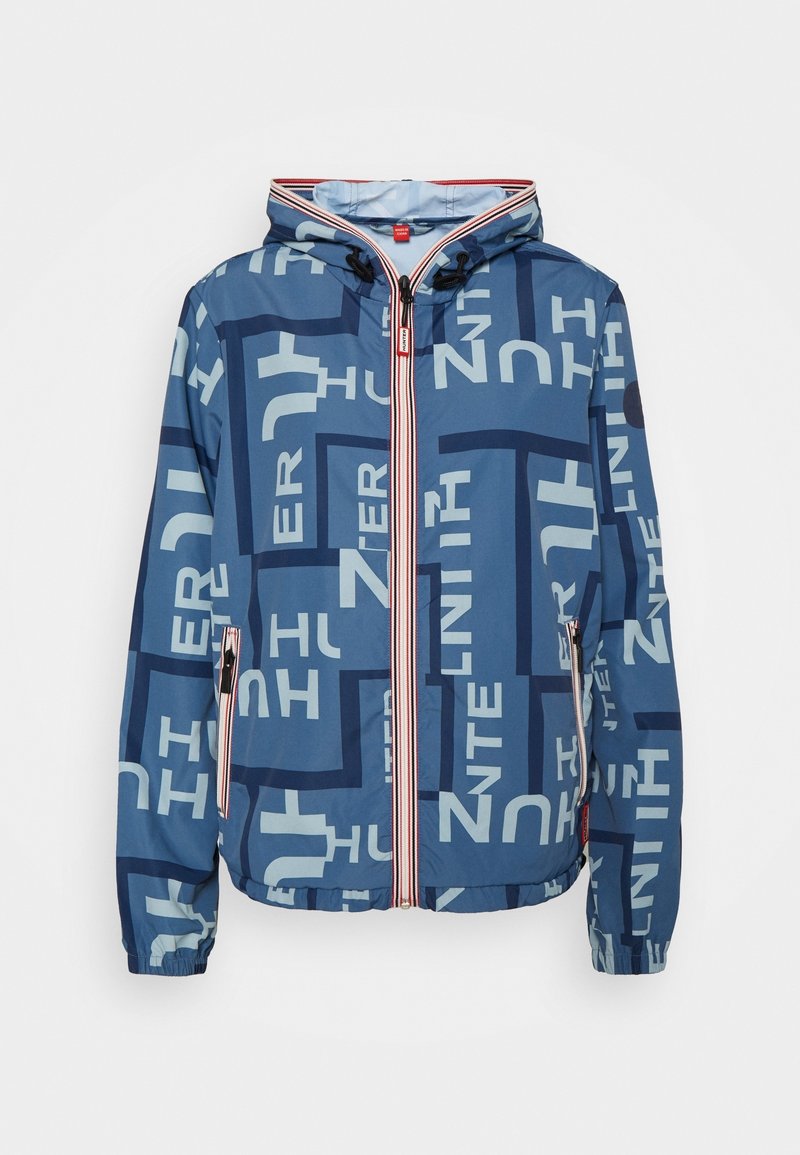 Niebieska kurtka z kapturem z geometṙcznym nadrukiem tekstowym, zapięciem na zamek, elastycznymi mankietami oraz czerwonymi i białymi paskami. Lekki materiał.