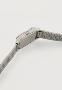 Ασημένιο μεταλλικό ρολόι χειρός με ορθογώνια κάσα, εξαγωνικό κορώνα και πλεκτό μεταλλικό μπρασελέ σε λευκό φόντο.