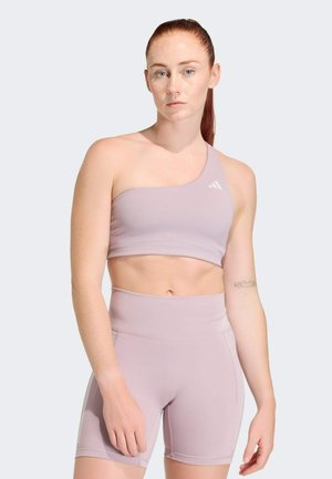 Světle fialová žebrovaná sportovní podprsenka s jedním ramenním popruhem, v kombinaci s vysokými šortkami ve stejné barvě. Jemné značení na podprsence.