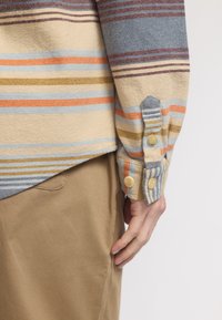 Overhemd met knopen in horizontale strepen in beige, blauw, oranje en bordeauxrood, met een gestructureerde stof en manchetten met twee knopen.