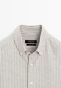 Overhemd met knopen en kraag, met afwisselende dunne verticale strepen in grijs en wit, en witte knopen. Het label luidt "Massimo Dutti."