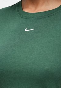 Πράσινο βαμβακερό μπλουζάκι με στρογγυλή λαιμόκοψη και κοντά μανίκια. Διαθέτει ένα μικρό λευκό λογότυπο Nike στην περιοχή του στήθους. Ομαλή υφή.