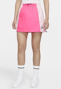 Jupe de sport rose et rose clair avec une taille élastique et un cordon de serrage, arborant le logo Nike, fabriquée en tissu lisse et léger.