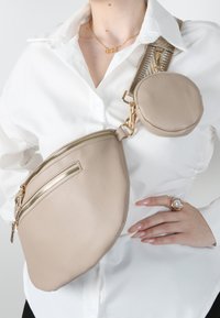 Borsa a tracolla in finta pelle beige con texture, due scomparti con zip, pochette rotonda removibile e dettagli in hardware dorato.