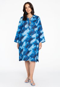 Blaue gemusterte Tunika-Kleid mit langen Ärmeln. Mit einem Schnür-Frontverschluss, lässiger Passform und seitlichen Schlitzen, aus leichtem Stoff gefertigt.