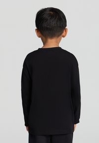 Maglietta nera a maniche lunghe realizzata in tessuto morbido, con scollo tondo e vestibilità regolare, presentando una texture liscia e senza motivi visibili.