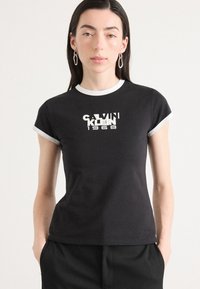 Black cotton t-shirt with short sleeves, white trim, and a graphic logo reading "CALVIN KLEIN 1968" in white and contrasting font styles.
