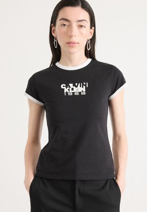 Camiseta de algodón negra de manga corta, con ribetes blancos y un logo gráfico que dice "CALVIN KLEIN 1968" en blanco y en estilos de fuente contrastantes.