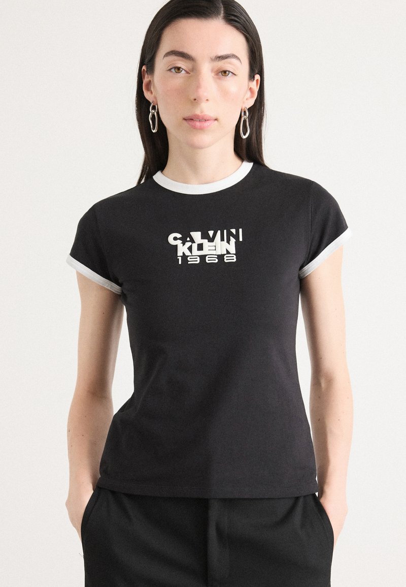 Black cotton t-shirt with short sleeves, white trim, and a graphic logo reading "CALVIN KLEIN 1968" in white and contrasting font styles.