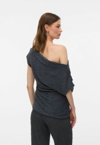 Mörkgrå off-shoulder topp med en texturerad, plisserad design och lös passform, kombinerad med matchande texturerade byxor.