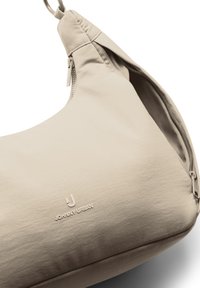 Beige schultertasche in Halbmondform mit Reißverschluss oben, der Marke "Johnny Urban", und einem Metallring am Ende des Riemens.