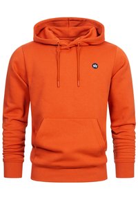 Orange hoodie tillverkad av mjukt tyg, med en framficka i kängurustil, ribbade ärmslut och en liten mörk logotyp på bröstet.