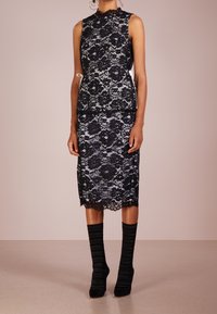 Black lace dress with a high neckline and sleeveless design, featuring intricate floral patterns and a fitted skirt. Paired with black ribbed socks.