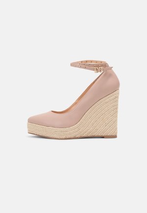 Chaussure à talon compensé beige avec plateforme tissée, bout pointu et bride de cheville ornée d'une boucle dorée et de détails œillets.