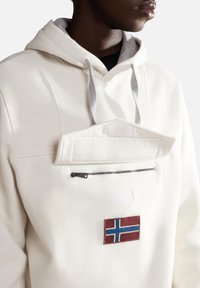 Biała bluza z kapturem ze szarymi sznurkami, z kieszenią z przodu oraz kieszenią zapinaną na suwak. Zawiera naszywkę z haftowaną norweską flagą.