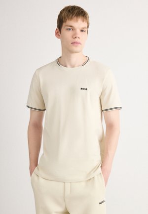 Beige cotton t-shirt with a crew neck, black trim on the collar and sleeves, featuring a small black "BOSS" logo on the chest.