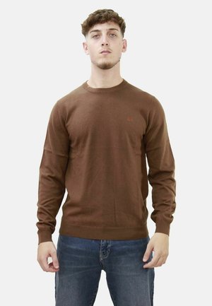 Maglione lavorato a maglia marrone con scollatura tonda, maniche lunghe e un logo discreto sul petto. La trama appare liscia e morbida.