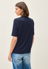 T-shirt bleu marine à manches courtes en tissu doux, avec un col rond et une coupe décontractée, associé à un jean bleu clair.